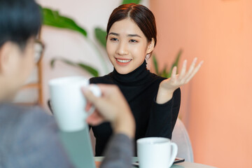 Asian woman sitting and chatting with colleagues in the coffee shop after work