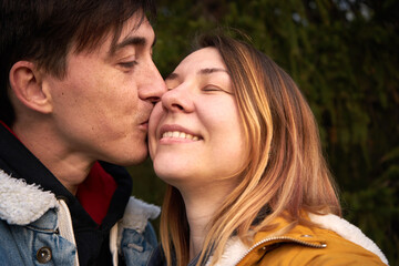 Obraz premium Enamored man kisses a smiling woman in a park.