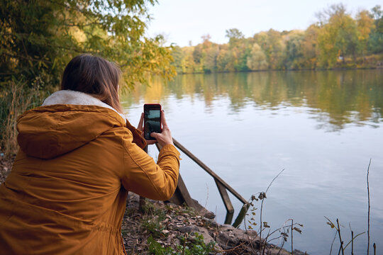 Beautiful woman taking pictures of the lake on a smartphone