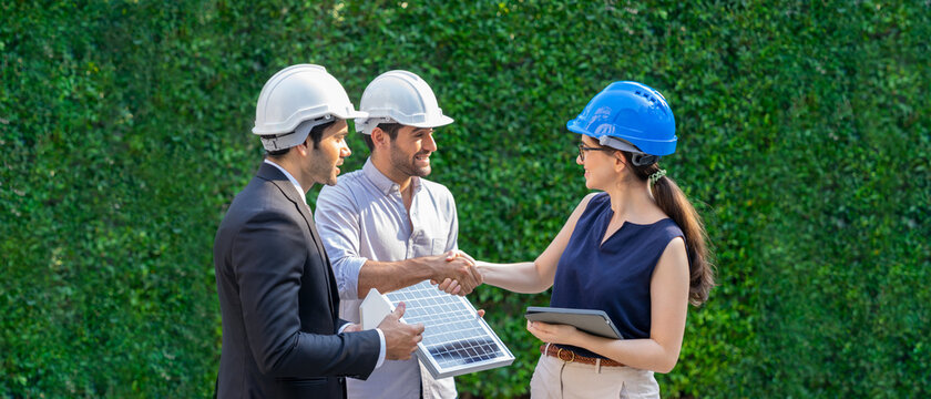 Successful teamwork. Female technician and businessman handshake after making an investment deal. Solar energy engineer holding a solar panel.  Concept of Photovoltaic solar, Ecology power.
