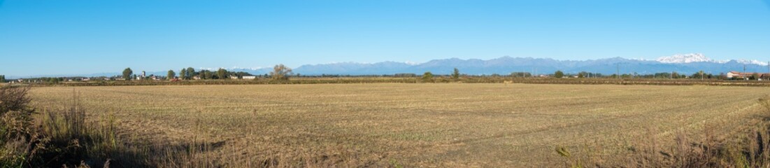 Fields in northern Italy with the Alpine chain in the background and on the left the town of San Nazzaro Sesia, province of Novara, Piedmont region. Panoramic view of the Po Valley 