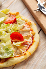 Chicken caesar pizza with tomatoes and lettuce
