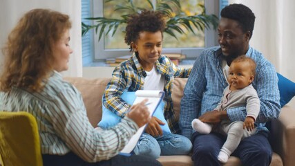 Social worker consulting smiling young single father with kids at home.