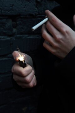 Close-up Of Person Igniting Cigarette With Lighter
