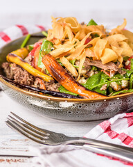 A serving of Lamb Salad in a round bowl with red and white striped napkin
