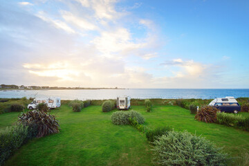 Camping site on the rocky shores of Brittany, France. Caravan trailer close-up. Dramatic sky. RV,...