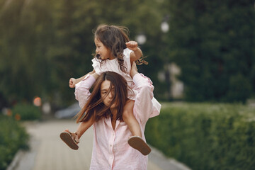 Beautiful family in a park. Woman in a blouse. Mother with daughter.