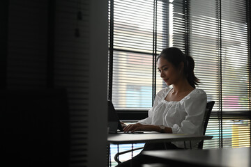 A young confident businesswoman employee is typing email on computer tablet at workplace.