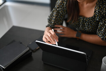 A young businesswoman or graphic designer is using stylus pen drawing on digital tabblet at her...