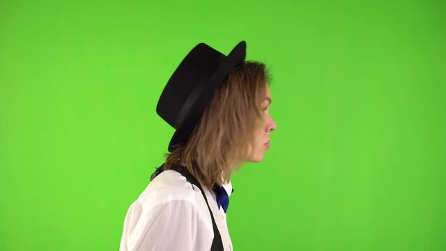 Profile of a Woman in a hat shaking her fist angrily on a green background. Swearing woman in a suit.