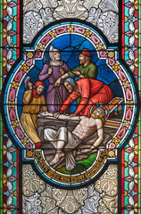 Fototapeta na wymiar VIENNA, AUSTIRA - OCTOBER 22, 2020: The Jesus is nailed to the crosss scene on the stained glass in in church Pfarrkirche Kaisermühlen by workroom Tiroler Glasmalerei-Anstalt from end of 19. cent..