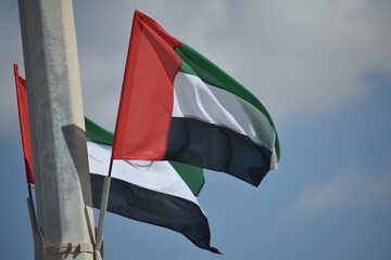 UAE flag waving in the sky, national symbol of UAE. UAE National Day. Celebration, freedom.
