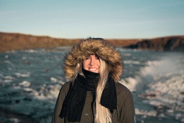 Blonde young woman in front of a waterfall in Iceland