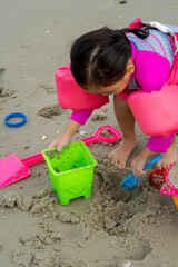 Portrait of  little toddler girl playing sand at the beach.