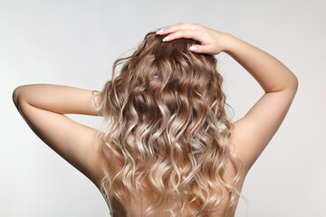Woman from backside on gray background. Female with curly hair