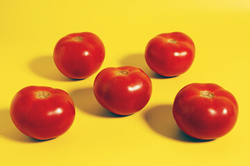 Ripe juicy red tomatoes on yellow background.