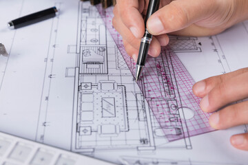 Hand over construction plans with yellow helmet. laptop and drawing tool