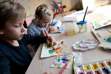 Children painting pictures with watercolor paints during art lesson. Pupils are concentrating on...