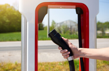 A man holds a charger plug for an electric car