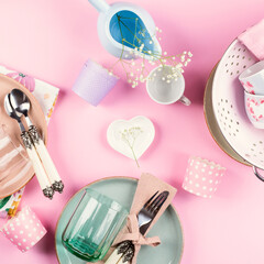 Pastel color ceramic and glass tableware with floral decor on pink background. Flat lay with modern dishes and crockery.