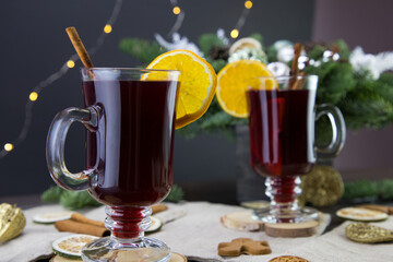 Mugs of warm wine with orange, cookies and cinnamon, dried fruit and spruce branches, Mulled wine close-up shot of warm wine