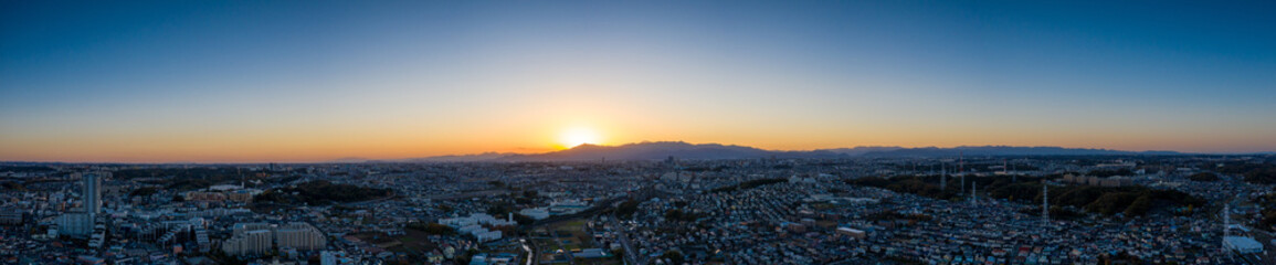 山に沈みゆく太陽と街並みのパノラマ