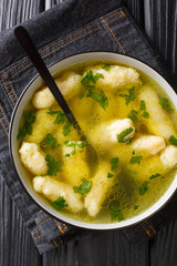 Clear soup with semolina dumplings close up in a dish on the table. vertical top view from above