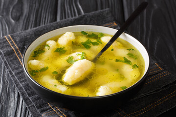 Homemade semolina dumplings in meat broth close-up in a plate on the table. horizontal