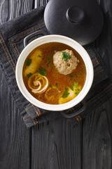 Beef broth Rindsuppe with pancake strips Frittaten, semolina dumplings, liver dumpling close-up in a saucepan on the table. Vertical top view from above