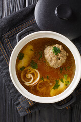 Rindsuppe Brown Beef Soup Recipe close-up in a saucepan on the table. Vertical top view from above