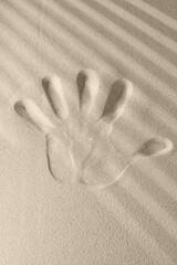 Texture of a sandy surface with the imprint of a person's left hand