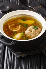 Beef broth Rindsuppe with pancake strips Frittaten, semolina dumplings, liver dumpling close-up in a saucepan on the table. Vertical