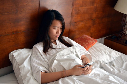 Woman Lying On Bed Pressing Mobile Phone