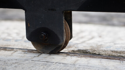 Portrait the metal wheels of rolling door gate, close-up shots with blurred concrete surface as background.