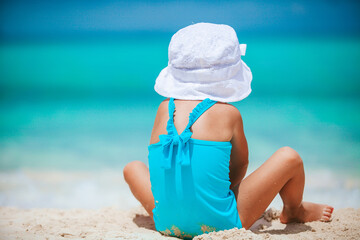 Little girl at tropical white beach making sand castle