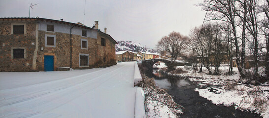 Panoramic of snowy village with roman bridge and river