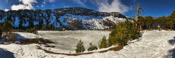 Panoramic of a frozen lagoon with snow and a shelter