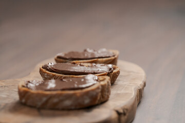 Ciabatta slices with chocolate spread on olive wood board