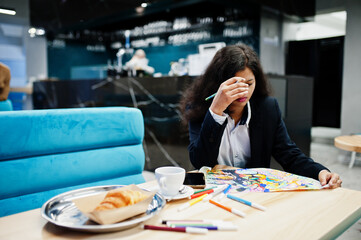 Indian artist woman wear formal paint picture, while sitting at cafe.