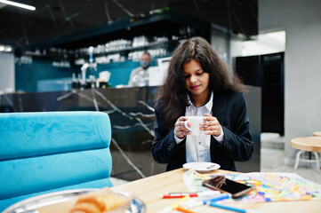 Indian artist woman wear formal paint picture and drink tea, while sitting at cafe.