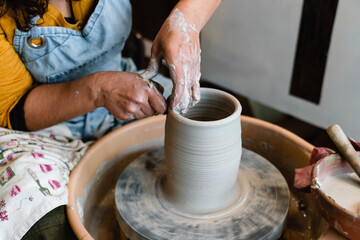 Potter making ceramic pot on the pottery wheel with hands
