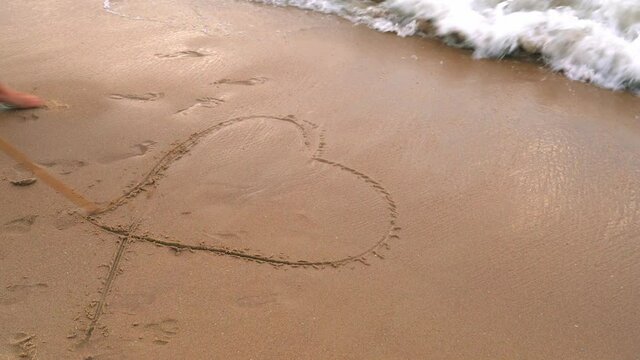drawing hearts in the sand lapping waves wash them away
