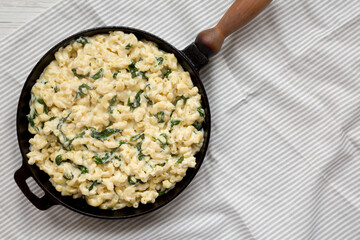 Homemade Spinach Mac and Cheese in a cast-iron pan on cloth, top view. Flat lay, overhead, from above. Copy space.