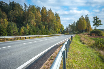 View of the highway road in the fall. Traveling background. Asphalt highway passing through the forest. Latvia. Baltic.