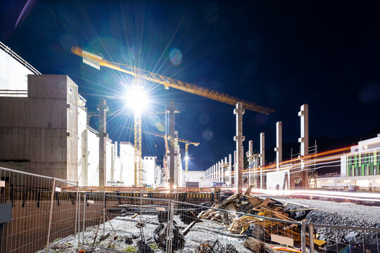 Floodlit tower crane on building construction site at night