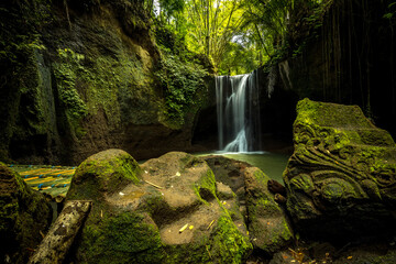 Beautiful waterfall in rainforest. Tropical landscape. Slow shutter speed, motion photography. Foreground with big stones. Environment concept. Suwat waterfall, Bali, Indonesia