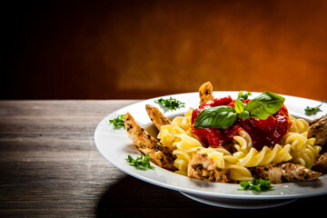 Roast chicken nuggets with fusilli and tomato sauce on wooden table