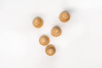 Wooden chess pieces. White pawns stand behind each other looking out from behind their comrades on a white background, focus on the second row of pawns, the view from the top