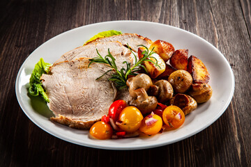 Roasted pork ham, champignons and fried potatoes on wooden table