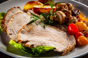 Roasted pork ham, champignons and fried potatoes on wooden table